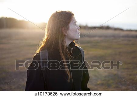 Teenage girl wearing backpack in field at sunset View Large Photo Image Stock Photograph - Teenage girl wearing backpack in field at sunset. Fotosearch