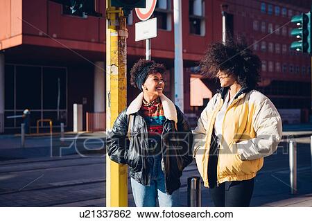 Two cool young female friends chatting in urban street View Large Photo Image Stock Image - Two cool young female friends chatting in urban street. Fotosearch