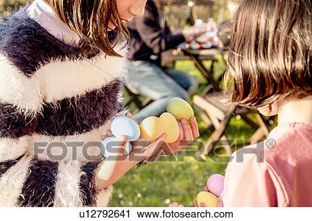 Two girl with handfuls of dyed Easter eggs at table, cropped View Large Photo Image Stock Image - Two girl with handfuls of dyed Easter eggs at table, cropped. Fotosearch