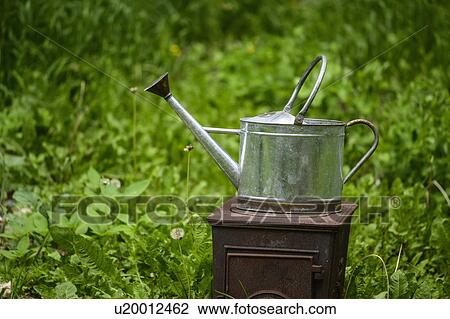 Stock Image - Watering can on old stove. Fotosearch