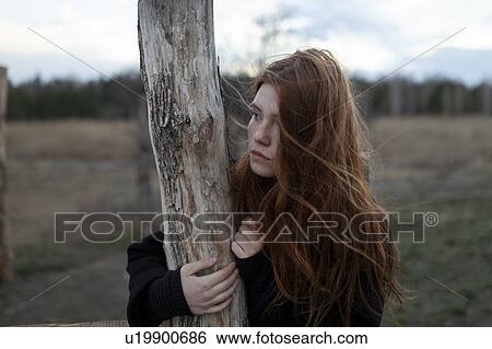 Windswept teenage girl by tree trunk View Large Photo Image Stock Photograph - Windswept teenage girl by tree trunk. Fotosearch