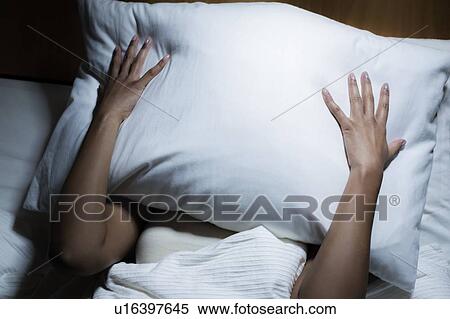 Woman covering her face with pillow View Large Photo Image Stock Photography - Woman covering her face with pillow. Fotosearch