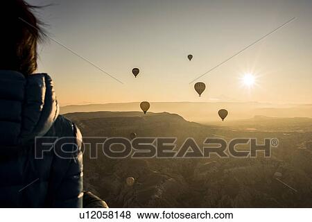 Woman enjoying view, hot air balloons flying in background, Greme, Cappadocia, Nevsehir, Turkey View Large Photo Image Stock Photo - Woman enjoying view, hot air balloons flying in background, Greme, Cappadocia, Nevsehir, Turkey. Fotosearch