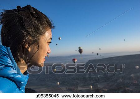 Woman enjoying view, hot air balloons flying in background, Greme, Cappadocia, Nevsehir, Turkey View Large Photo Image Stock Photography - Woman enjoying view, hot air balloons flying in background, Greme, Cappadocia, Nevsehir, Turkey. Fotosearch