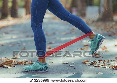 Woman exercising with resistance band outdoors View Large Photo Image Stock Photo - Woman exercising with resistance band outdoors. Fotosearch