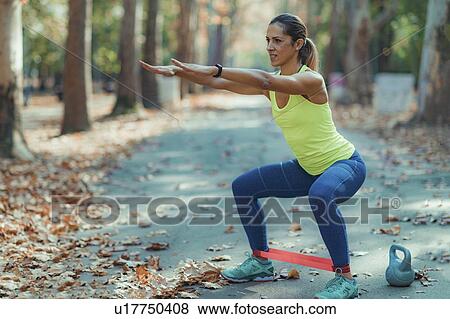Stock Photo - Woman exercising with resistance band outdoors. Fotosearch