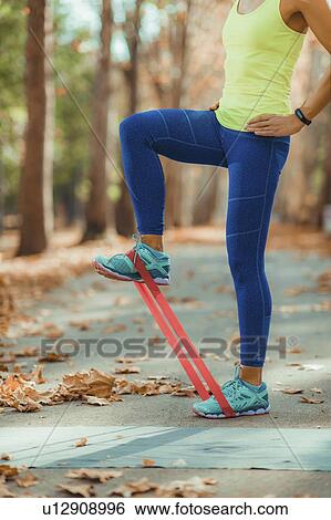 Stock Photograph - Woman exercising with resistance band outdoors. Fotosearch