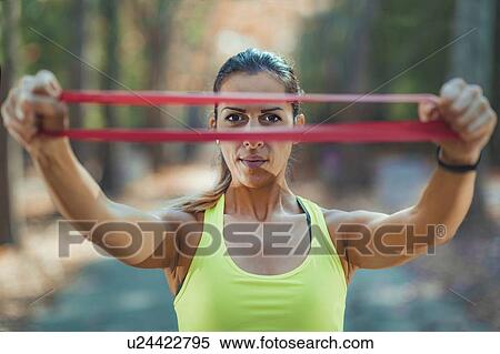 Stock Photography - Woman exercising with resistance band outdoors. Fotosearch