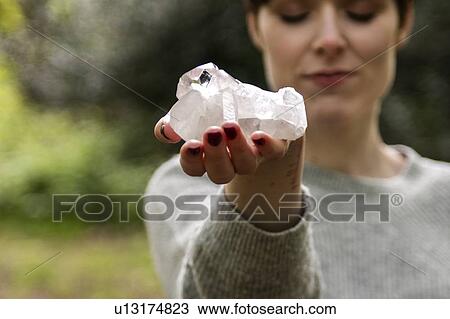 Stock Image - Woman holding healing crystal for Reiki. Fotosearch