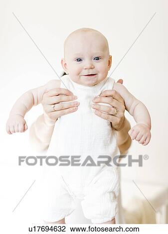 Stock Image - Woman holding out her baby boy. Fotosearch