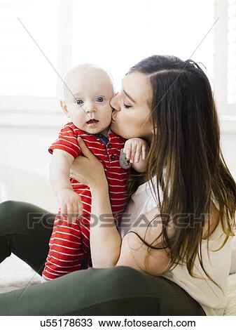 Woman kissing her baby boy's cheek View Large Photo Image Stock Image - Woman kissing her baby boy's cheek. Fotosearch