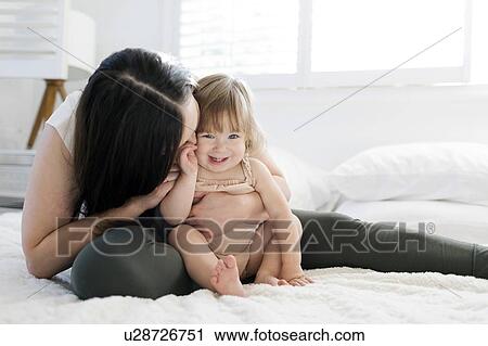 Stock Image - Woman kissing her daughter's cheek. Fotosearch