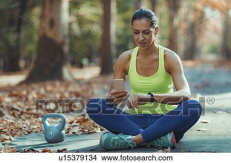 Woman looking at smart watch after outdoor training View Large Photo Image Picture - Woman looking at smart watch after outdoor training. Fotosearch