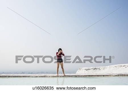 Stock Photography - Woman looking down at thermal pool, Pamukkale, Denizli, Turkey. Fotosearch