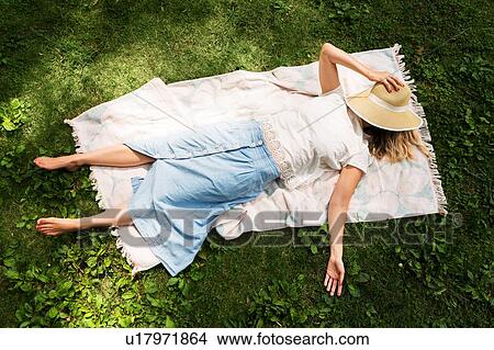 Woman lying on blanket in park View Large Photo Image Picture - Woman lying on blanket in park. Fotosearch