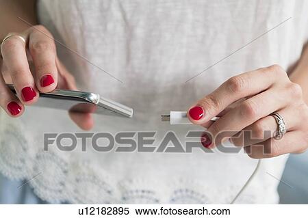 Stock Photography - Woman plugging charger into smart phone. Fotosearch