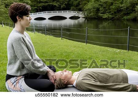 Woman practising Reiki on grass lawn by river, London, UK View Large Photo Image Stock Image - Woman practising Reiki on grass lawn by river, London, UK. Fotosearch