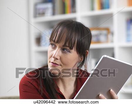 Woman relaxing at home on her digital tablet which she uses for social media, email and internet shopping View Large Photo Image Stock Image - Woman relaxing at home on her digital tablet which she uses for social media, email and internet shopping. Fotosearch