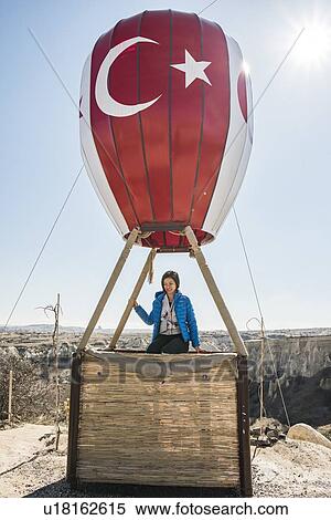 Woman sitting on basket of hot air balloon overlooking fairy chimney valley, Greme, Cappadocia, Nevsehir, Turkey View Large Photo Image Stock Photography - Woman sitting on basket of hot air balloon overlooking fairy chimney valley, Greme, Cappadocia, Nevsehir, Turkey. Fotosearch