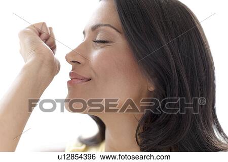 Stock Photograph - Woman smelling perfume on her wrist. Fotosearch