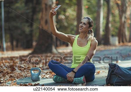 Picture - Woman taking selfie after training outdoors. Fotosearch