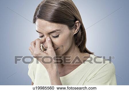 Stock Image - Woman touching bridge of nose. Fotosearch