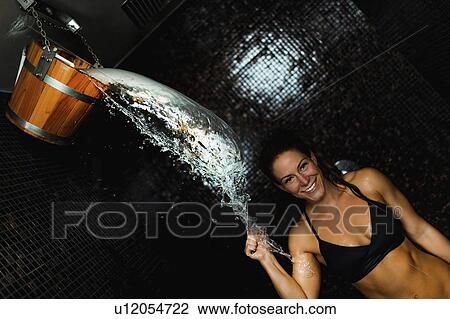 Stock Image - Woman under ice cold shower bucket. Fotosearch