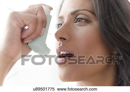 Stock Photography - Woman using asthma inhaler. Fotosearch