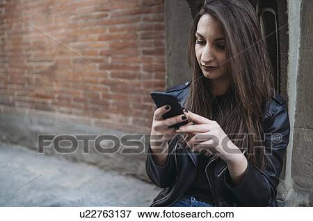 Stock Photo - Woman using smartphone on steps. Fotosearch