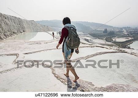 Stock Photograph - Woman walking across thermal pools, Pamukkale, Denizli, Turkey. Fotosearch