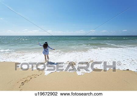 Stock Image - Woman walking on beach in Lisbon, Portugal. Fotosearch