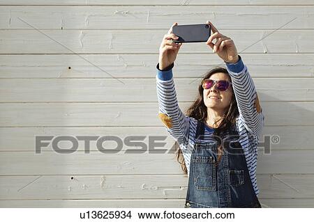 Woman wearing sunglasses taking selfie View Large Photo Image Picture - Woman wearing sunglasses taking selfie. Fotosearch