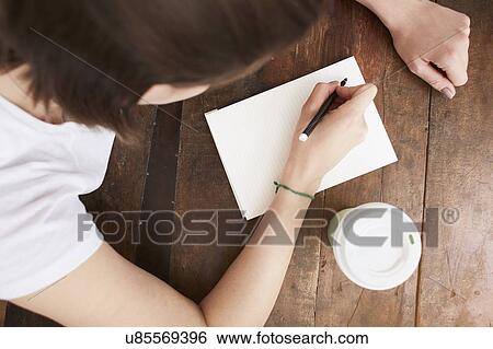 Woman writing on notebook at coffee break View Large Photo Image Stock Photograph - Woman writing on notebook at coffee break. Fotosearch