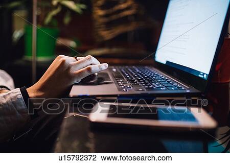 Stock Image - Women at cafe table typing on laptop, close up. Fotosearch