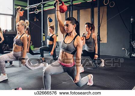 Women training in gym, lifting kettle bells with legs outstretched View Large Photo Image Stock Photograph - Women training in gym, lifting kettle bells with legs outstretched. Fotosearch