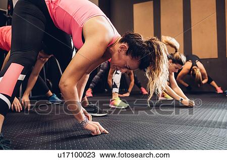 Stock Image - Women training in gym, touching floor, side view. Fotosearch