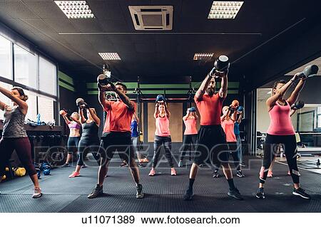 Women training in gym with male trainers, lifting kettle bells View Large Photo Image Stock Photo - Women training in gym with male trainers, lifting kettle bells. Fotosearch