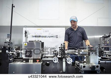 Worker adjusting printing machine in print factory View Large Photo Image Picture - Worker adjusting printing machine in print factory. Fotosearch