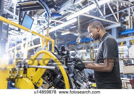 Stock Photo - Worker assembling dashboard on production line in car factory. Fotosearch