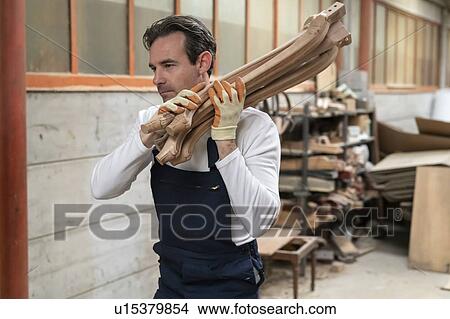 Worker carrying wooden furniture legs on shoulder in factory View Large Photo Image Picture - Worker carrying wooden furniture legs on shoulder in factory. Fotosearch