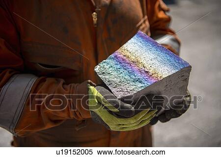 Worker holding fractured block of titanium alloy with coloured iridescence in titanium recycling plant View Large Photo Image Stock Photography - Worker holding fractured block of titanium alloy with coloured iridescence in titanium recycling plant. Fotosearch