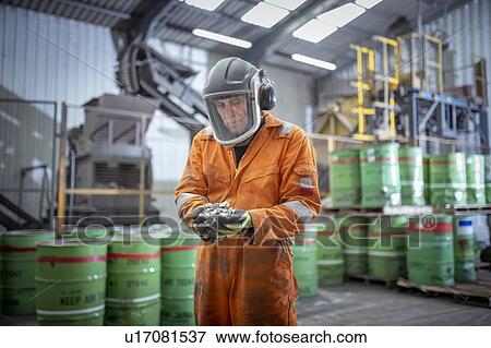 Stock Photo - Worker holding titanium sample in crushing plant in titanium recycling plant. Fotosearch