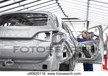 Stock Photo - Worker inspecting car body in paint inspection area in car factory. Fotosearch