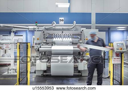 Stock Image - Worker inspecting food packaging in food factory. Fotosearch