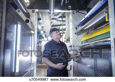 Worker inspecting interior of printing machine in print factory View Large Photo Image Stock Photo - Worker inspecting interior of printing machine in print factory. Fotosearch
