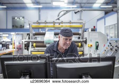 Picture - Worker inspecting screen in print factory. Fotosearch