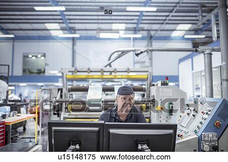 Stock Photography - Worker inspecting screen in print factory. Fotosearch