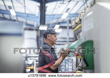 Worker loading plastic packaging in print machine in print factory View Large Photo Image Stock Photograph - Worker loading plastic packaging in print machine in print factory. Fotosearch