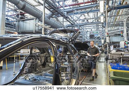 Stock Image - Worker on car production line in car factory. Fotosearch