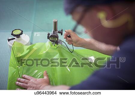 Picture - Worker testing plastic packaging material in print factory. Fotosearch